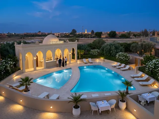 Pool at dusk with the white bar beyond, lounge chairs and small outdoor dining tables